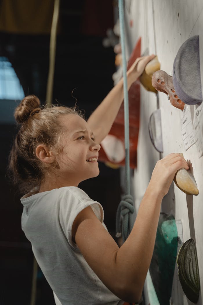 why-choose-us Young girl bouldering indoors, showcasing determination and strength during wall climb.